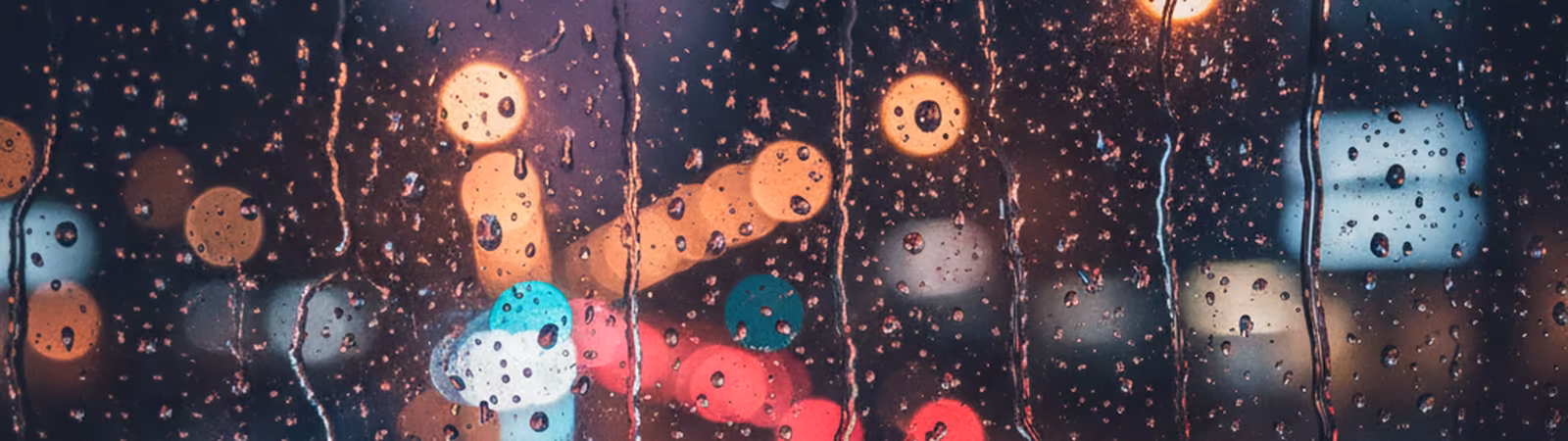 Rain on a window with magenta city lights behind