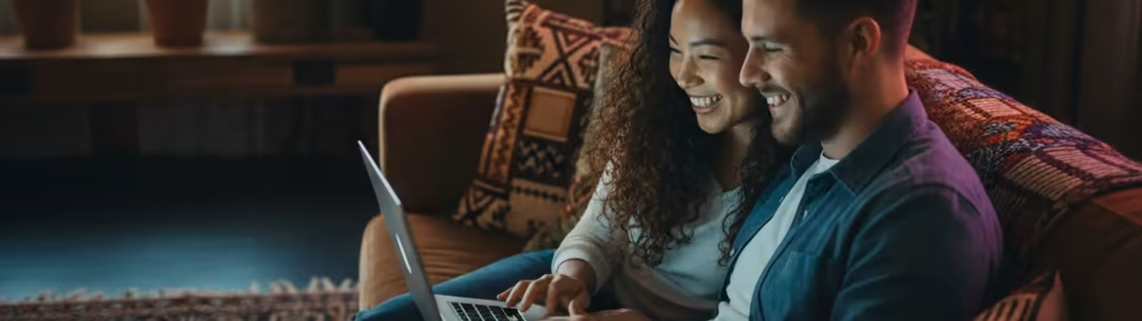 Couple browsing a laptop together on a couch